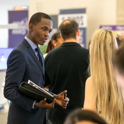 Person in a suit holding a tablet in a business setting.